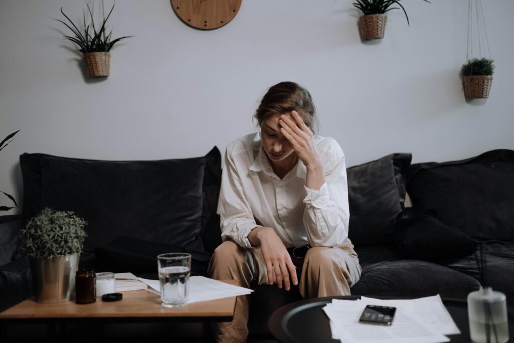 A woman sitting on a couch with her head in her left hand. 