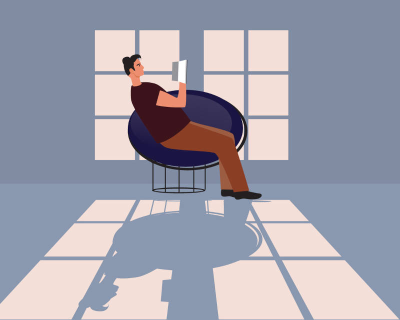 A cartoon of a man reading a book alone in a room, signifying introversion.