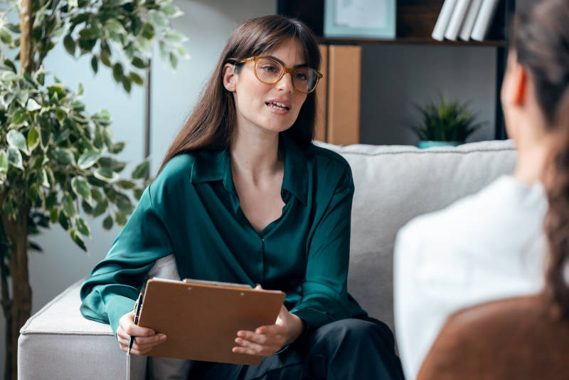 A woman therapist talking with her patient about the differences between therapists, psychiatrists, and psychologists.